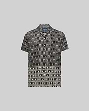 Kids Keon Tencel Shirt, a black short-sleeve camp collar shirt featuring a relaxed fit and an all-over white repeating Psycho Bunny skull and crossbones logo pattern.