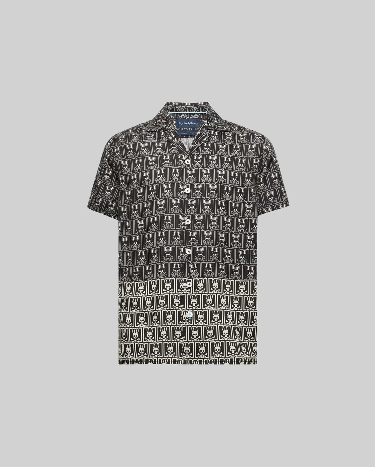 Kids Keon Tencel Shirt, a black short-sleeve camp collar shirt featuring a relaxed fit and an all-over white repeating Psycho Bunny skull and crossbones logo pattern.