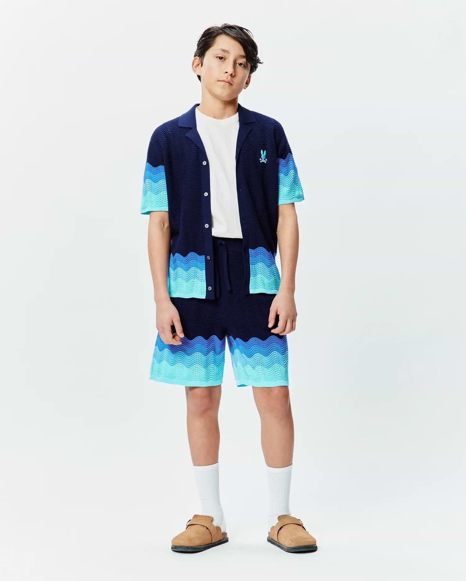 Kids Holden Oversized Knit Shirt and matching shorts set in navy blue with wavy gradient blue stripes, featuring a relaxed fit, textured knit fabric, and a small embroidered Psycho Bunny logo on the chest. (4)