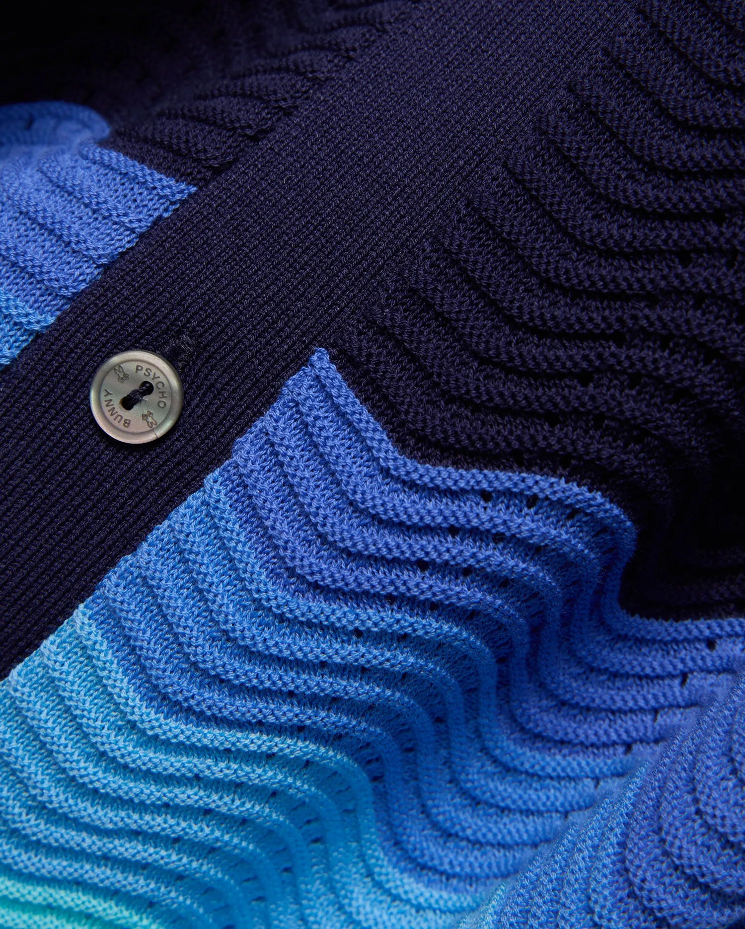 Kids Holden Oversized Knit Shirt, a navy to vibrant blue gradient knit with a distinctive wavy texture and subtle open-knit details, secured by a Psycho Bunny branded button. (6)