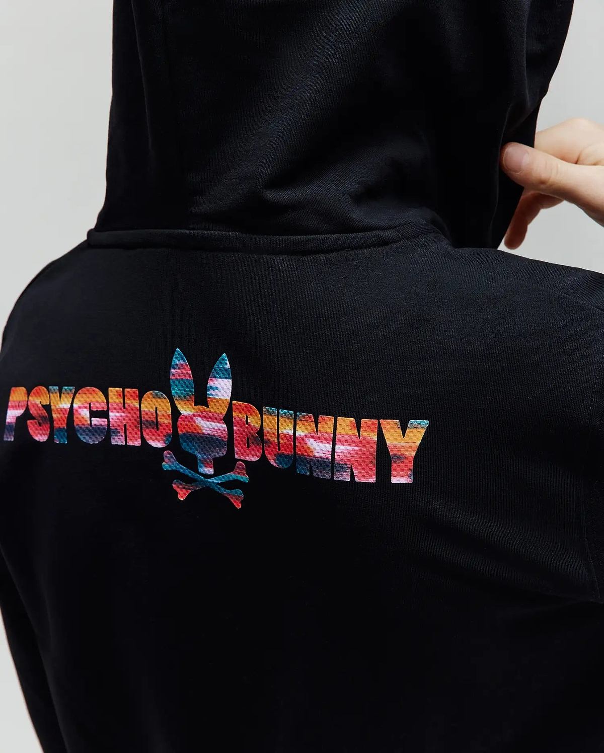 Kids Raphael French Terry Full Zip Hoodie in black, featuring a large, vibrant abstract multicolor Psycho Bunny text and bunny skull logo on the upper back, with a classic fit.