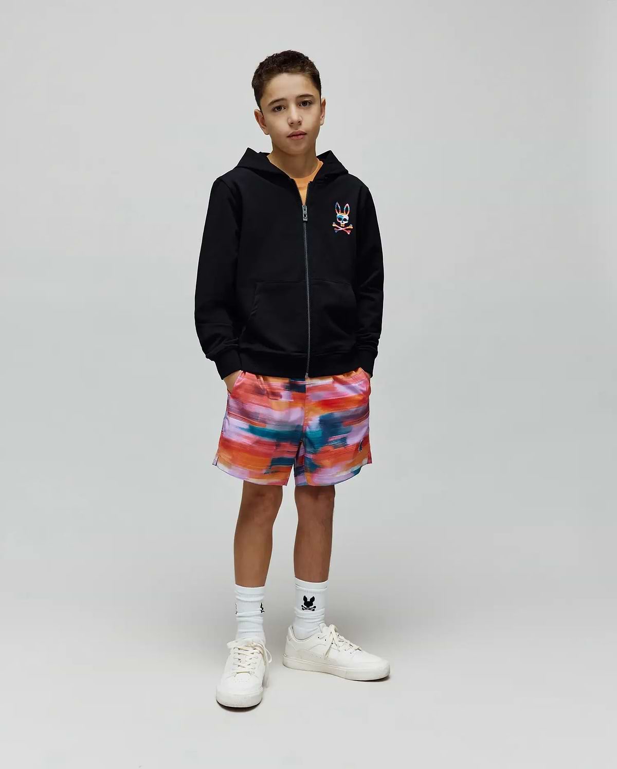 Kids Raphael French Terry Full Zip Hoodie in black with a colorful embroidered Psycho Bunny logo on the chest, paired with vibrant multi-color abstract print shorts and white socks featuring a small black bunny logo.