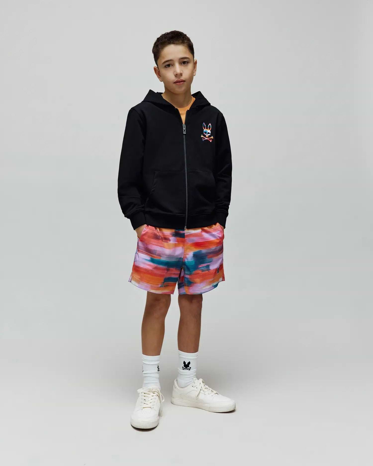 Kids Raphael French Terry Full Zip Hoodie in black with a colorful embroidered Psycho Bunny logo on the chest, paired with vibrant multi-color abstract print shorts and white socks featuring a small black bunny logo.