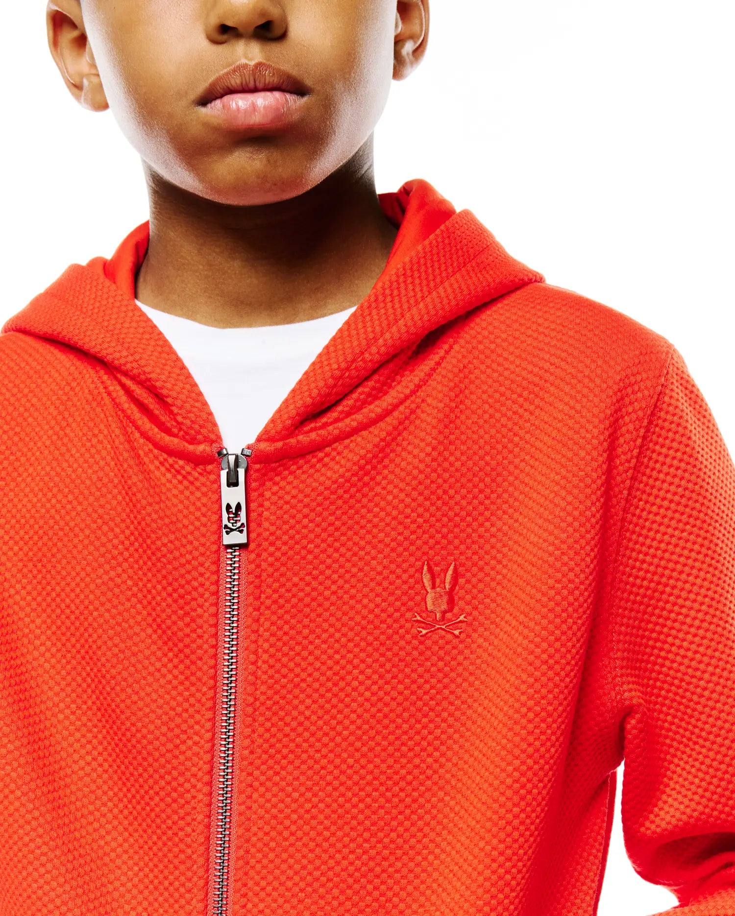 Kids Marc Textured Full Zip Hoodie in vibrant orange, featuring a textured knit fabric, small embroidered Psycho Bunny skull logo on the left chest, and a branded zipper pull. (2)