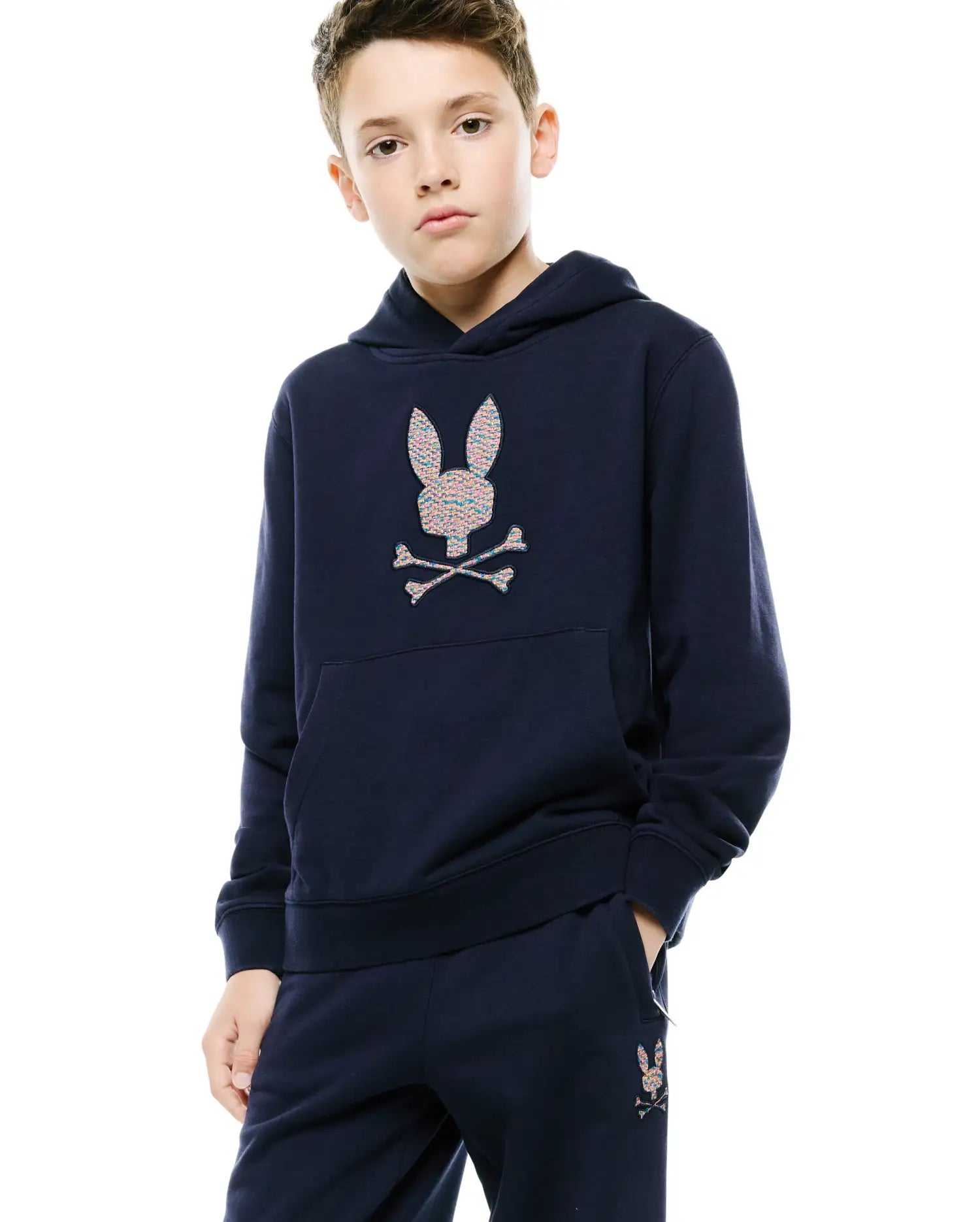Kids Darcy Hoodie and matching navy french terry sweatpants, featuring a relaxed fit. A large multicolor embroidered Psycho Bunny skull logo adorns the chest, with a smaller one on the left thigh.