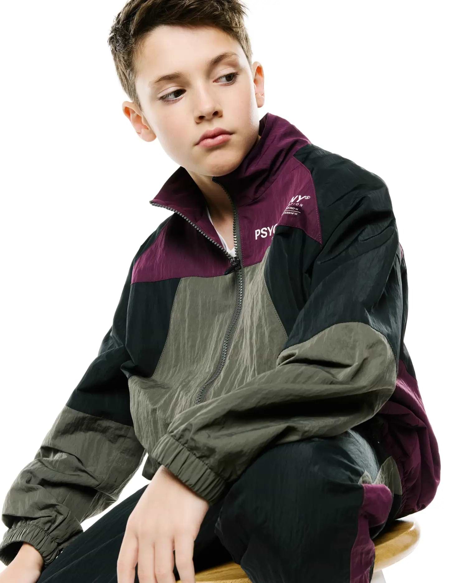 Kids Alder Nylon Colorblock Jacket in plum, olive green, and black, featuring a relaxed fit, full zip, and white Psycho Bunny text logo with NY® and coordinates on the chest.