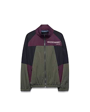 Kids Alder Nylon Colorblock Jacket in olive green, black, and deep purple, featuring a full zip, stand collar, and large white Psycho Bunny chest logo with Designed For Disruption text. Relaxed fit, crinkled nylon.
