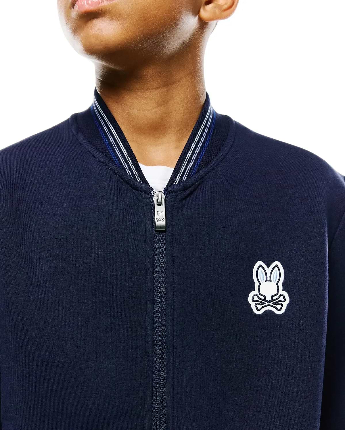 Kids Jaydon Track Jacket, navy smooth jersey, classic fit, full-zip with branded pull, ribbed collar with white and blue stripes, and an embroidered white and light blue Psycho Bunny skull logo on the left chest.