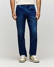 Mens Ace Knit Denim Pant in dark blue knit denim with subtle fading, a classic fit, and a small orange Psycho Bunny tag on the coin pocket.