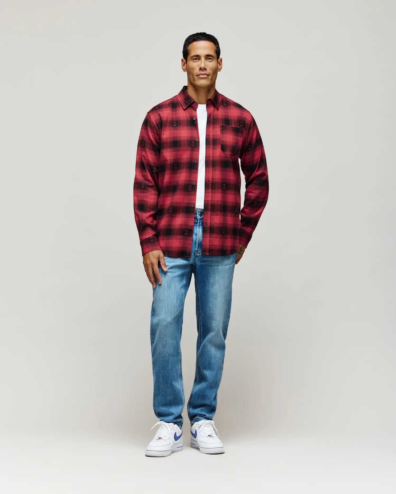 Red and black plaid flannel shirt with subtle all-over Psycho Bunny skull pattern, classic fit, layered over a white jersey t-shirt, paired with light wash Mens Emerson Denim Pant.