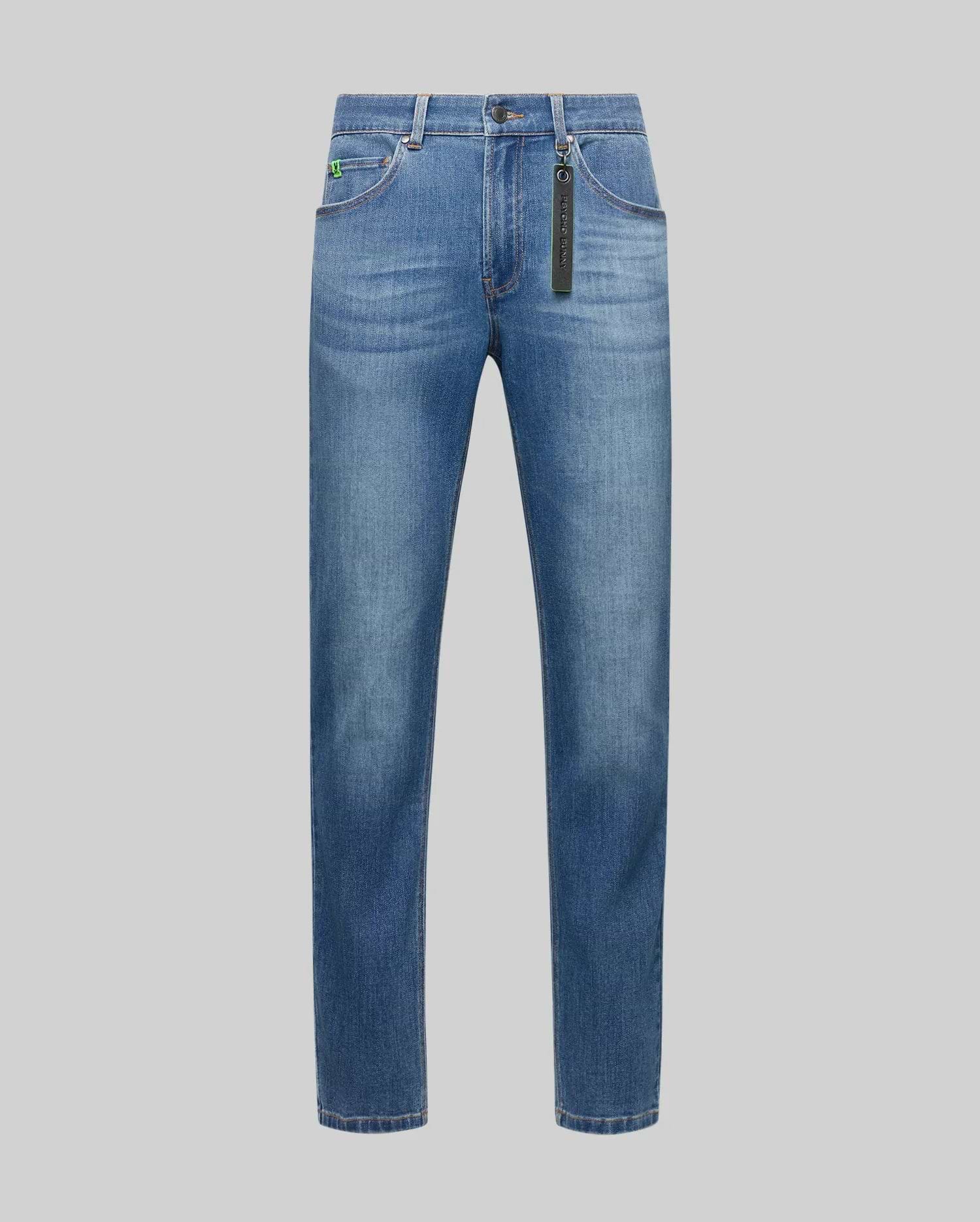 Mens Emerson Denim Pant, classic fit blue faded denim jeans with a small embroidered green bunny skull logo on the coin pocket and a black Psycho Bunny keychain.