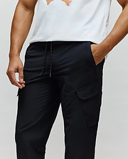 Mens Luka Cargo Pant, black, relaxed fit with smooth fabric, featuring a drawstring waist with orange flecks and a small tonal embroidered Psycho Bunny skull logo on the right cargo pocket.