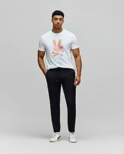 White classic fit jersey t-shirt with a large, colorful watercolor Psycho Bunny skull logo on the chest, paired with black slim fit Mens Luka Cargo Pant featuring a drawstring waist and side pockets.