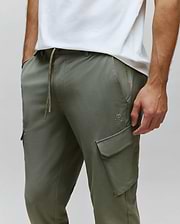 Mens Luka Cargo Pant in olive green, featuring a relaxed fit, smooth fabric, drawstring waist with speckled cord, and a small tonal embroidered Psycho Bunny skull logo above the left cargo pocket.