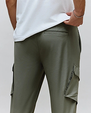 Mens Luka Cargo Pant in olive green, a relaxed fit style crafted from smooth jersey fabric, featuring prominent side cargo pockets and a debossed Psycho Bunny text logo above the back pocket.