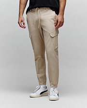 Mens Luka Cargo Pant in light beige, featuring a drawstring waist, relaxed tapered fit, and functional side cargo pockets in smooth woven fabric.