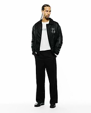 Black satin-like bomber jacket with a large white Psycho Bunny skull logo, a white jersey t-shirt with black Psycho Bunny text, and relaxed fit Black Mens Aidan Chino Pant. (4)