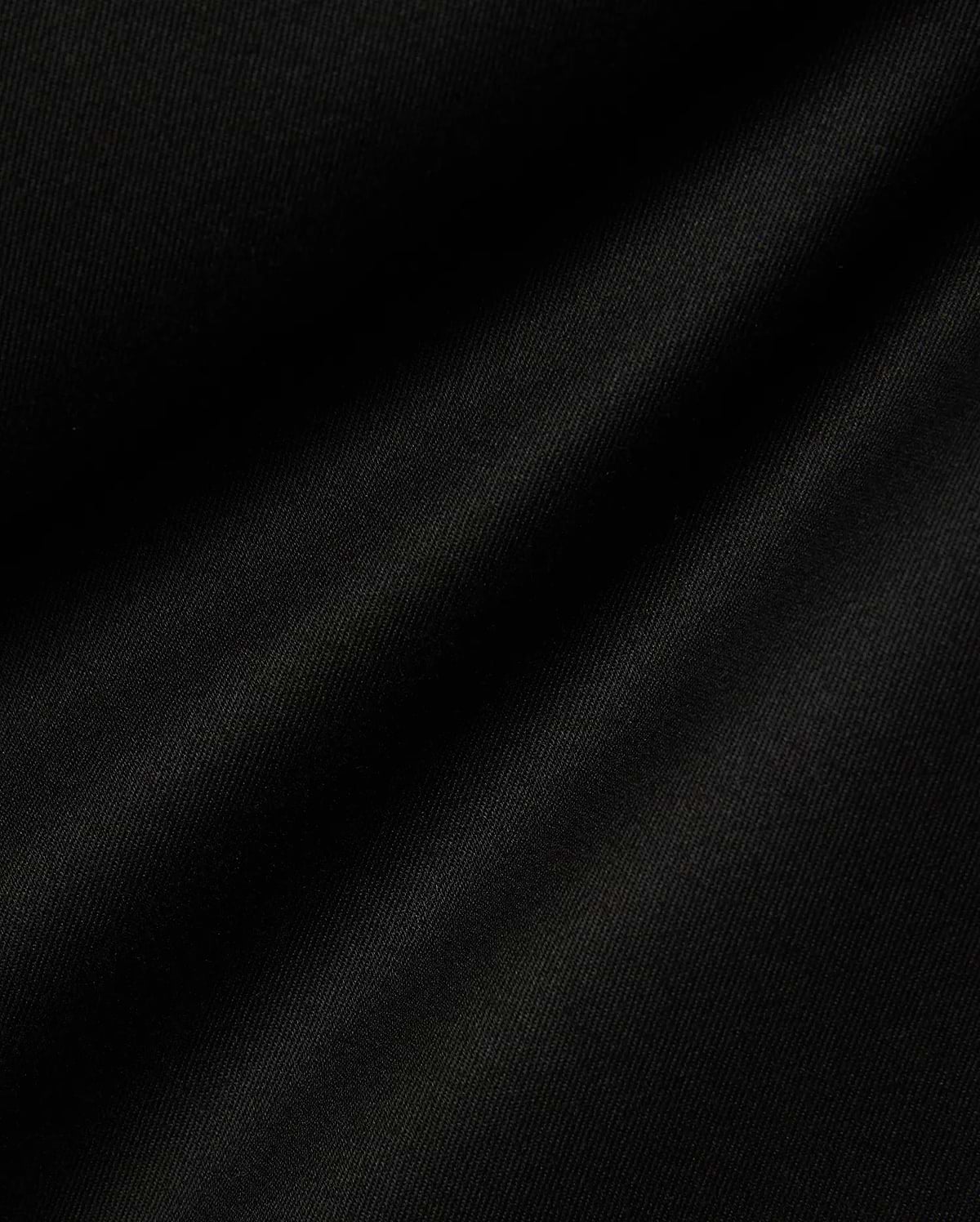 Mens Aidan Chino Pant in deep black, featuring a finely woven twill fabric with distinct diagonal ridges, creating a smooth texture and soft, undulating folds that suggest a comfortable drape. (6)