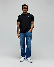 Black classic fit jersey t-shirt with a small embroidered light blue Psycho Bunny skull logo on the left chest, paired with relaxed fit medium blue washed MENS ACE KNIT DENIM PANT.