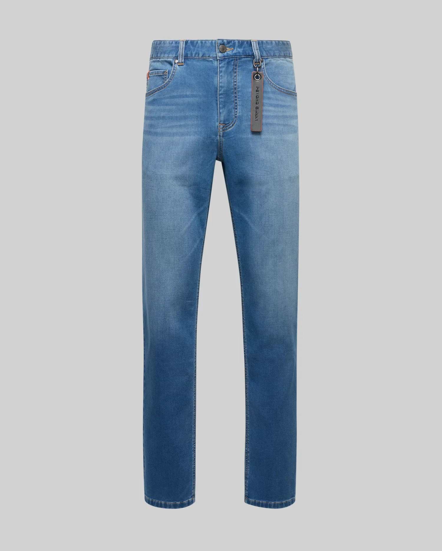 Mens Ace Knit Denim Pant in light blue washed knit denim, classic fit, with five-pocket styling, a small red embroidered bunny logo on the coin pocket, and a dark grey Psycho Bunny brand tag.