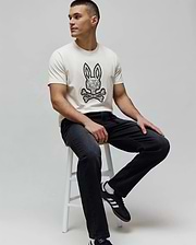 Cream classic fit jersey t-shirt with a large black and white intricate Psycho Bunny skull logo graphic on the chest, paired with dark grey Mens Ace Knit Denim Pant.