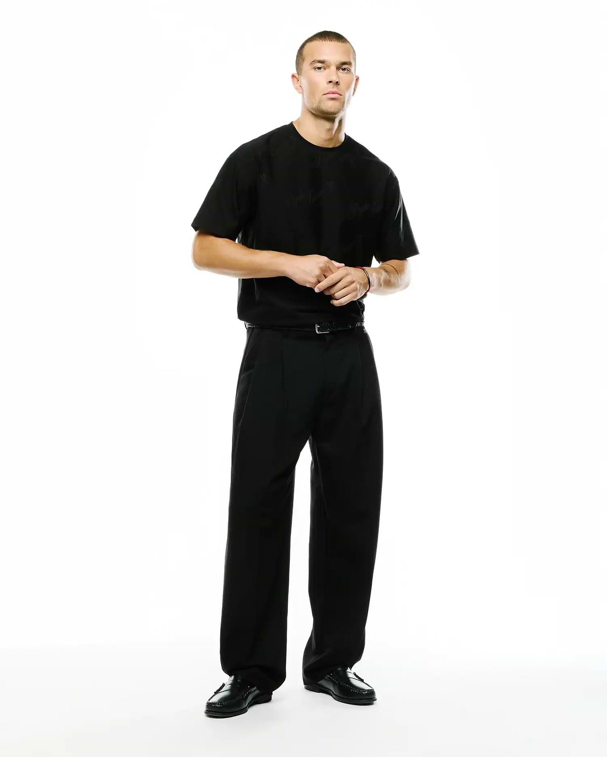 Black relaxed-fit jersey t-shirt featuring a subtle tonal Psycho Bunny skull logo on the left chest, paired with Men's Wayde Wide-Leg Pleated Pants in a smooth black fabric. (1)