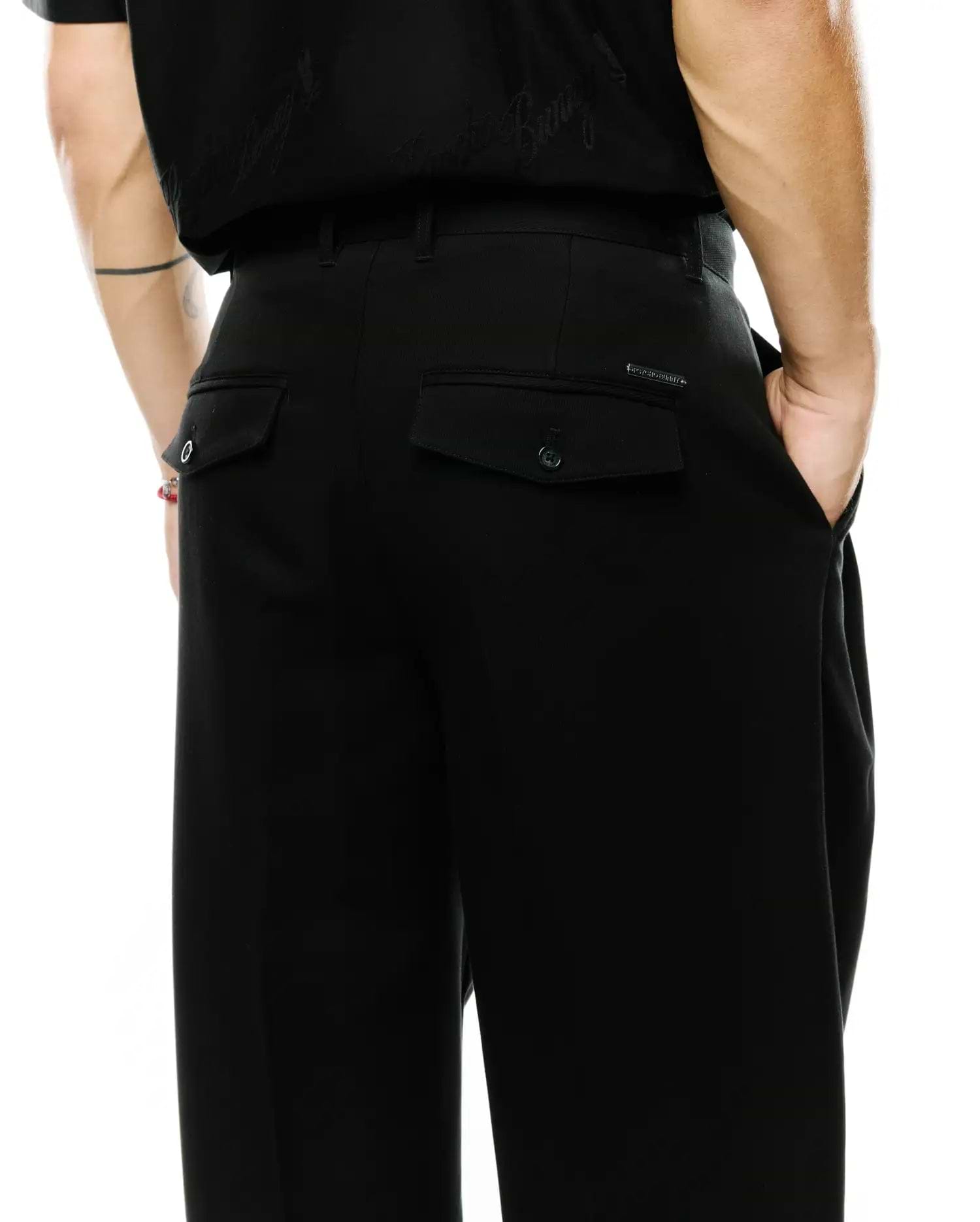 Men's Wayde Wide-Leg Pleated Pants in black, featuring a smooth fabric, wide-leg fit, two rear flap pockets with buttons, and a small metal Psycho Bunny logo tag above the right pocket. (3)