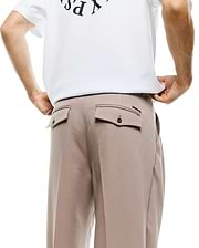 Men's Wayde Wide-Leg Pleated Pants in light beige, featuring back flap pockets with dark buttons and a small black brand tag, paired with a white relaxed-fit jersey t-shirt with a partial dark graphic print. (3)