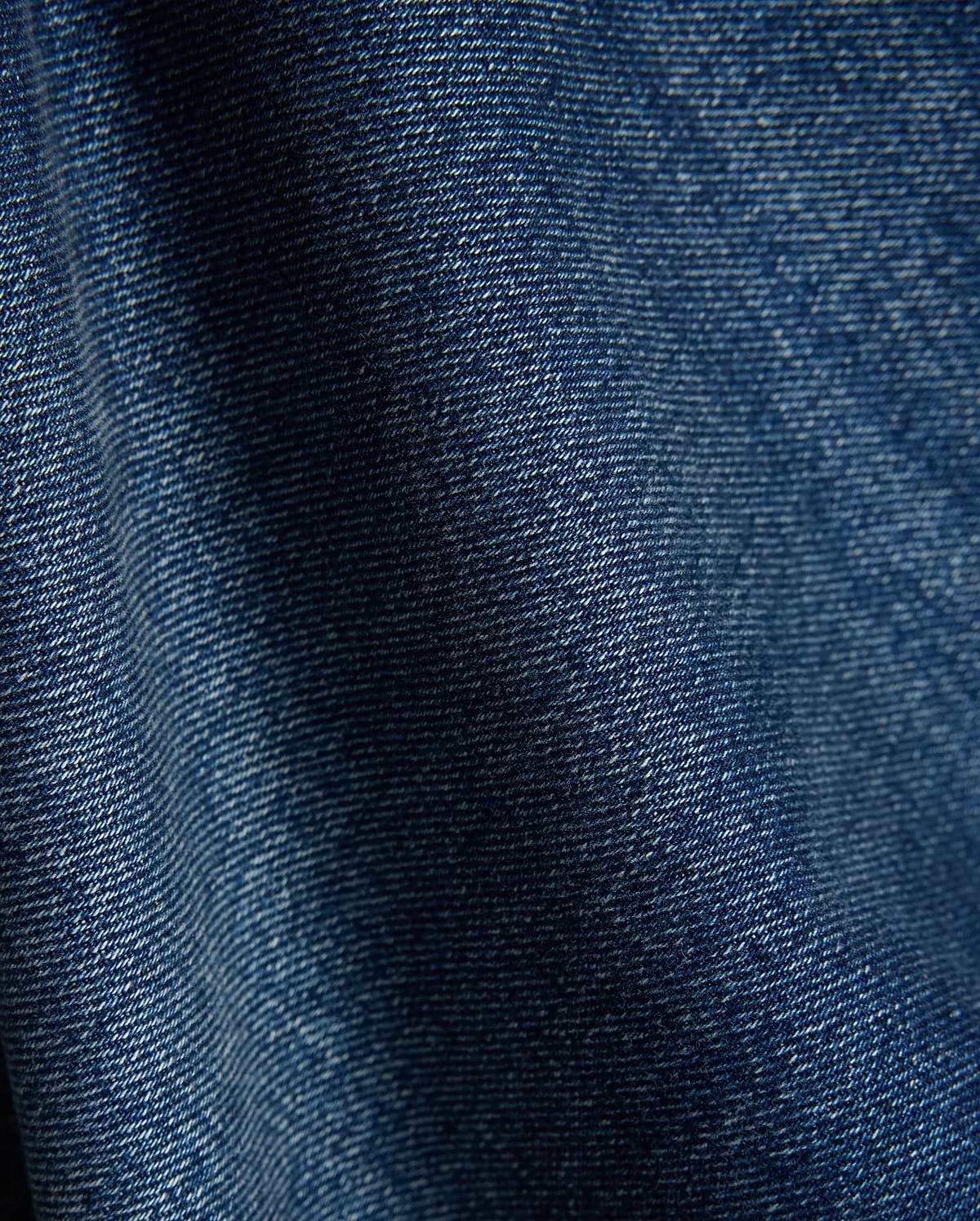 Mens Beck Denim Relaxed Pant in a rich, medium blue wash, showcasing a durable twill weave with subtle white thread accents and natural folds, creating a comfortable, lived-in texture.