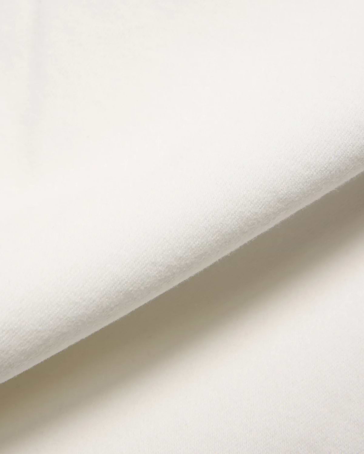 Mens Emerson Denim Pant in a crisp, creamy white, showcasing a premium, soft-touch denim fabric with a subtle, refined twill weave, gently folded to reveal its luxurious texture.