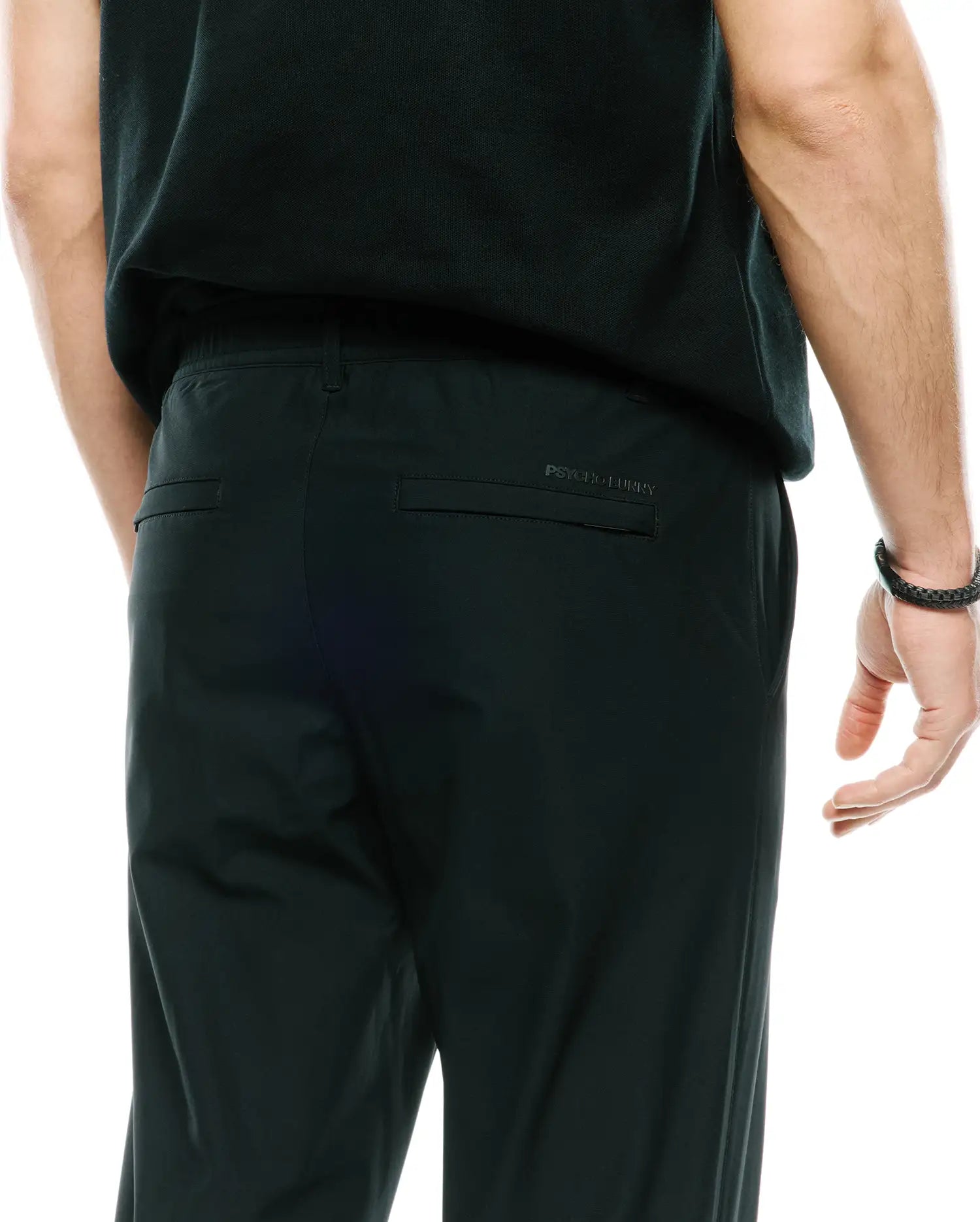 Mens Edward 10k Tapered Pant in dark forest green, featuring a relaxed fit, smooth performance fabric, elasticated waist, and a subtle debossed Psycho Bunny text logo on the back right pocket flap.