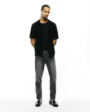 Black jersey t-shirt, black relaxed short-sleeve shirt with small embroidered Psycho Bunny skull on left chest, and Mens Emerson Denim Pant in dark grey wash.