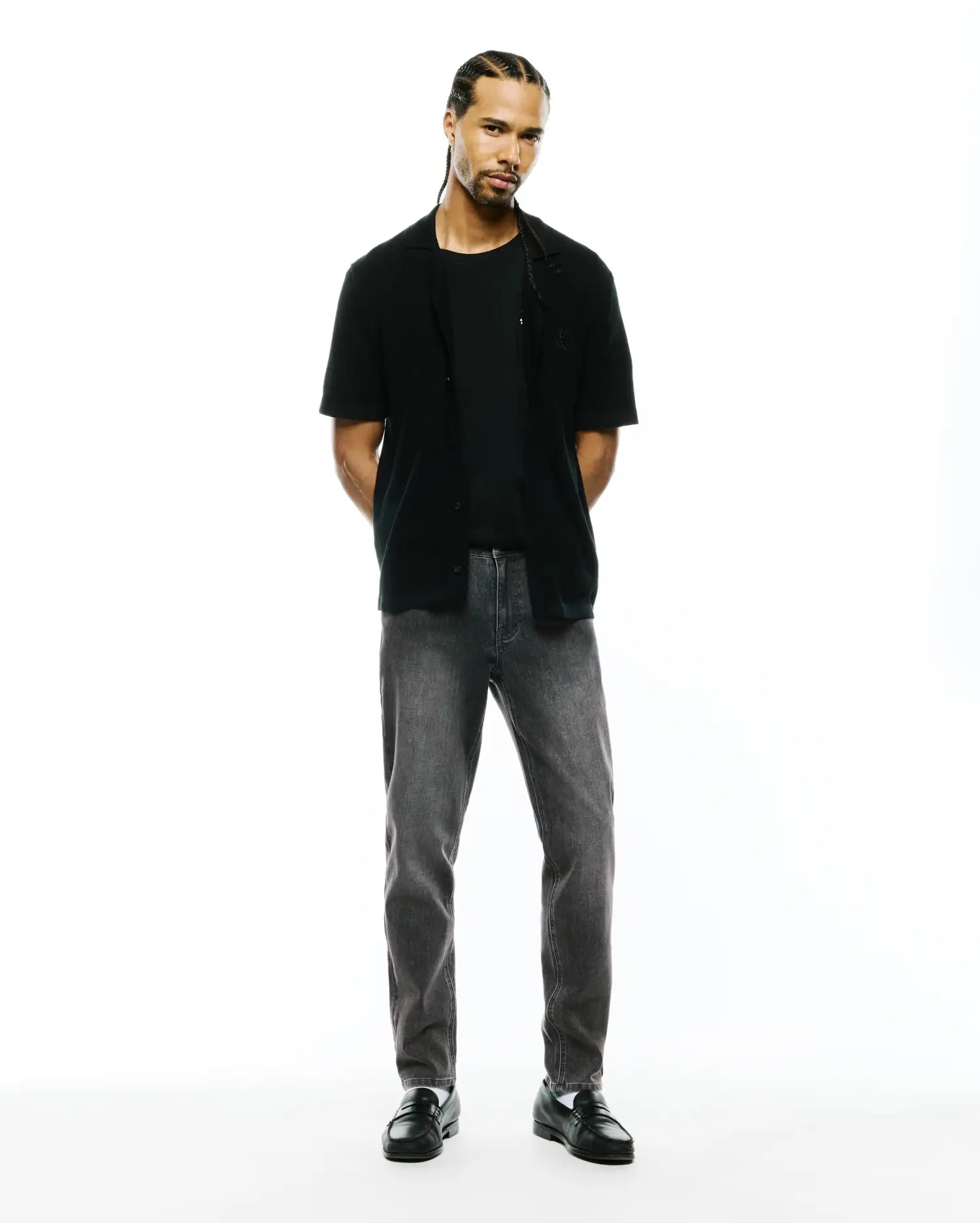Black jersey t-shirt, black relaxed short-sleeve shirt with small embroidered Psycho Bunny skull on left chest, and Mens Emerson Denim Pant in dark grey wash.