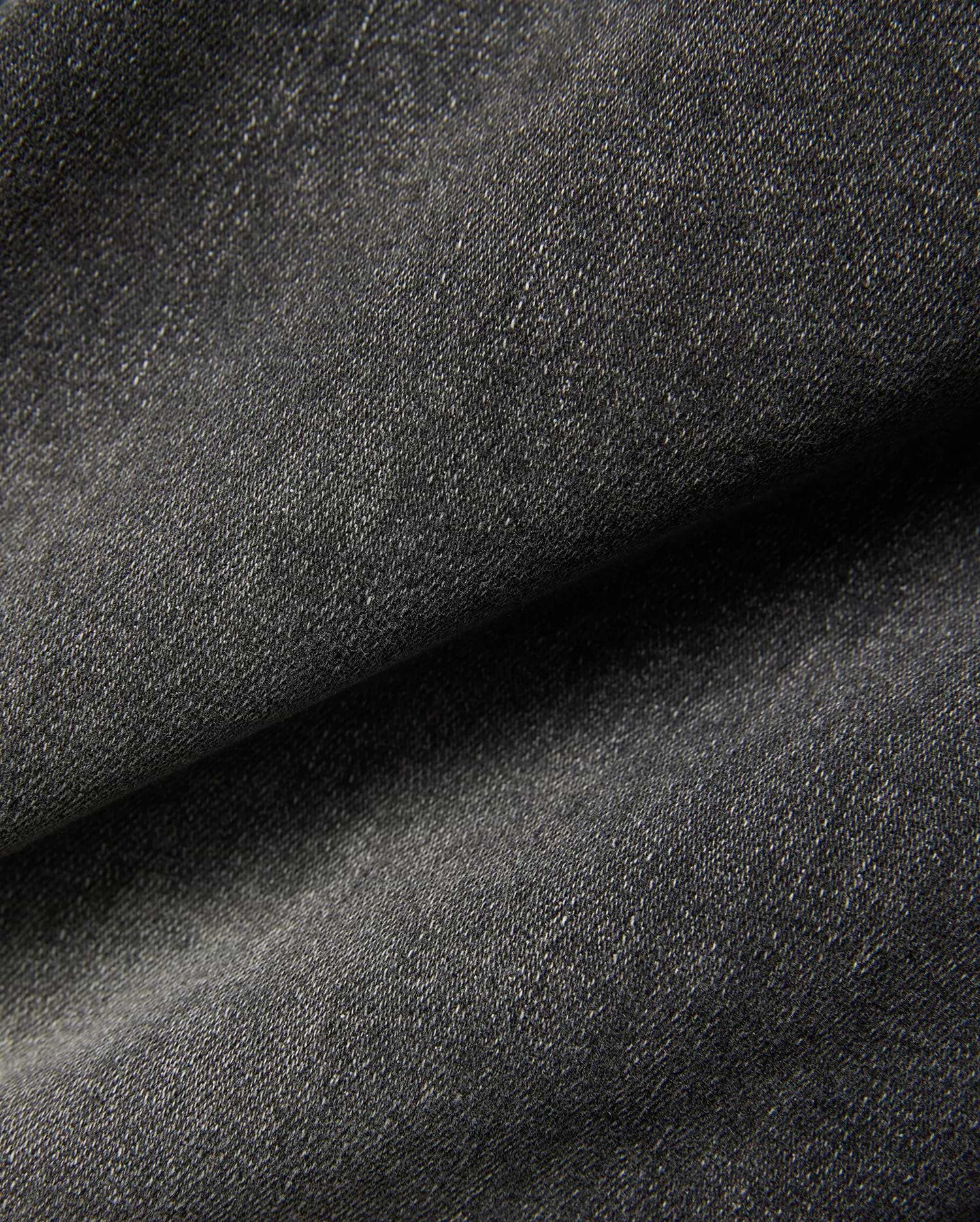 Mens Emerson Denim Pant featuring a dark charcoal grey denim fabric with a visible twill weave and subtle light flecks, creating a textured, washed appearance.