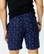 Mens Brad Linen Short 8 1/2, navy blue with a light blue all-over pattern of palm trees and Psycho Bunny skull logos in a scalloped design, classic fit linen blend.
