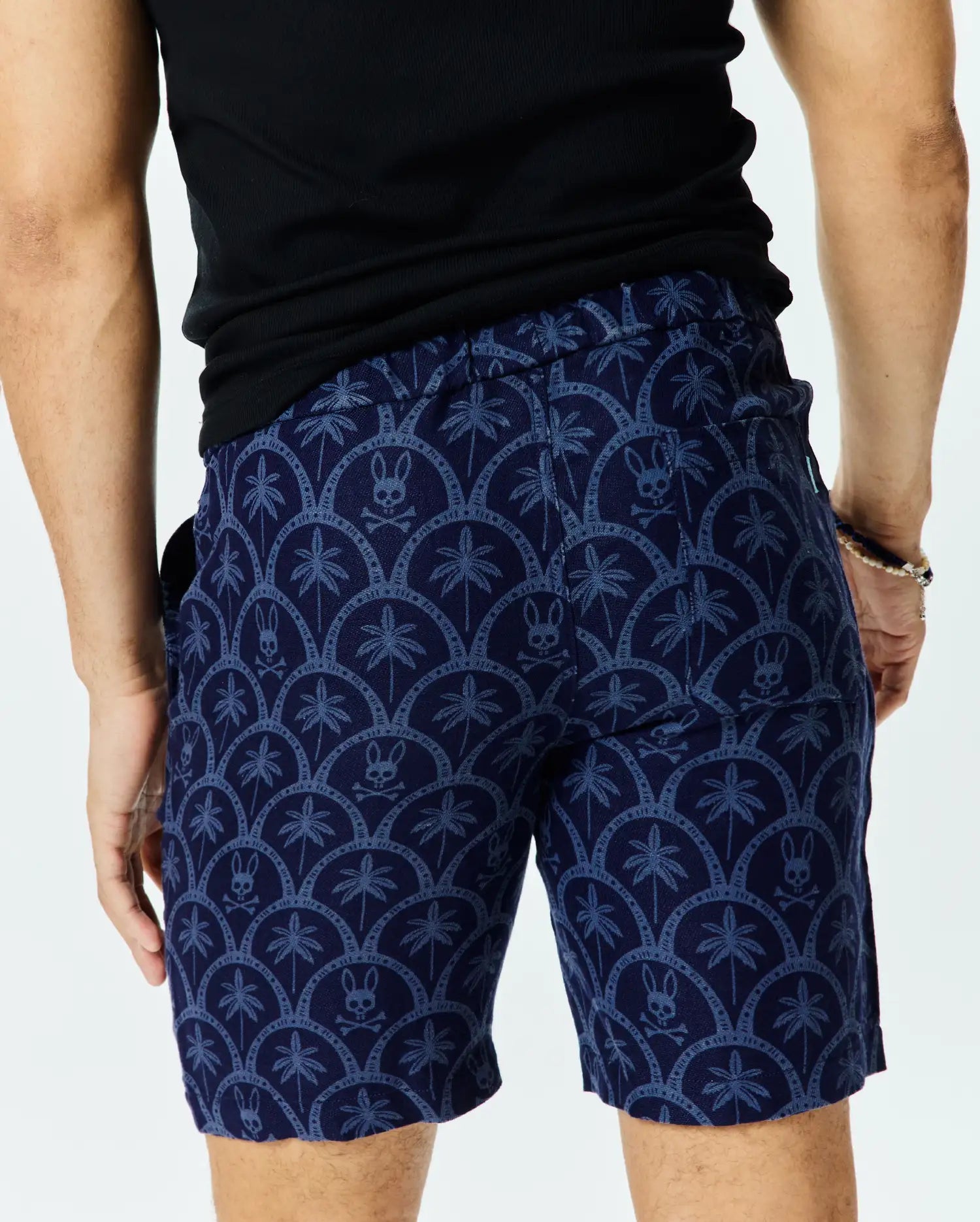 Mens Brad Linen Short 8 1/2, navy blue with a light blue all-over pattern of palm trees and Psycho Bunny skull logos in a scalloped design, classic fit linen blend.