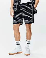 Mens Nick Tencel Short 7, black with an all-over white Psycho Bunny skull logo pattern, featuring white border stripes on the sides and hem, in a relaxed fit smooth Tencel fabric.