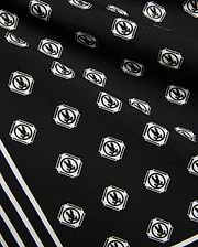 Mens Nick Tencel Short 7, black fabric with all-over white Psycho Bunny skull logo pattern in square frames, featuring bold white diagonal stripes. Smooth Tencel texture.