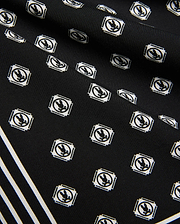 Mens Nick Tencel Short 7, black fabric with all-over white Psycho Bunny skull logo pattern in square frames, featuring bold white diagonal stripes. Smooth Tencel texture.