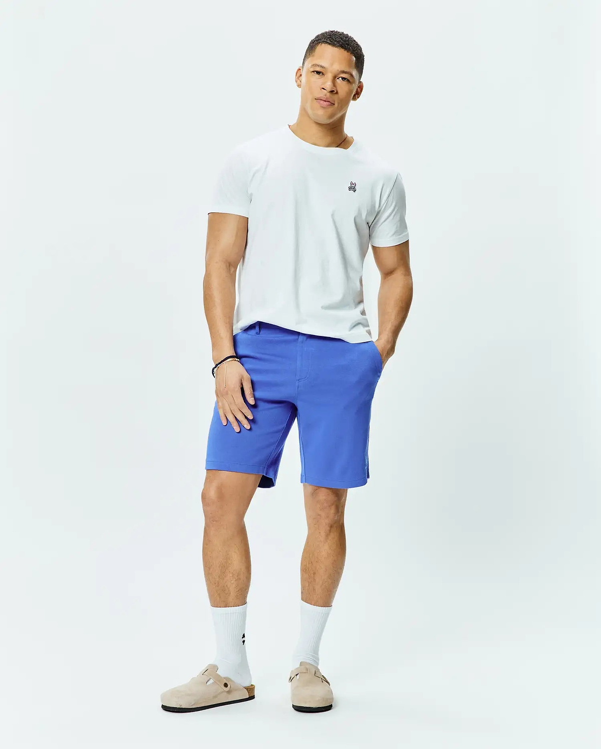 White classic fit jersey t-shirt featuring a small embroidered multi-color Psycho Bunny skull logo on the left chest, paired with vibrant blue MENS SHIRO TWILL SHORT.