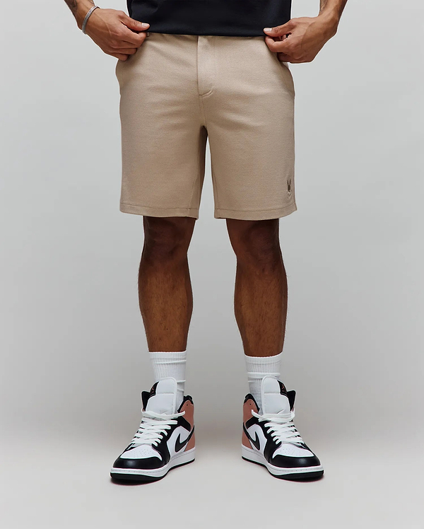 Mens Shiro Twill Short, a classic fit beige twill short featuring a subtle texture and a small embroidered Psycho Bunny skull logo on the lower left leg.