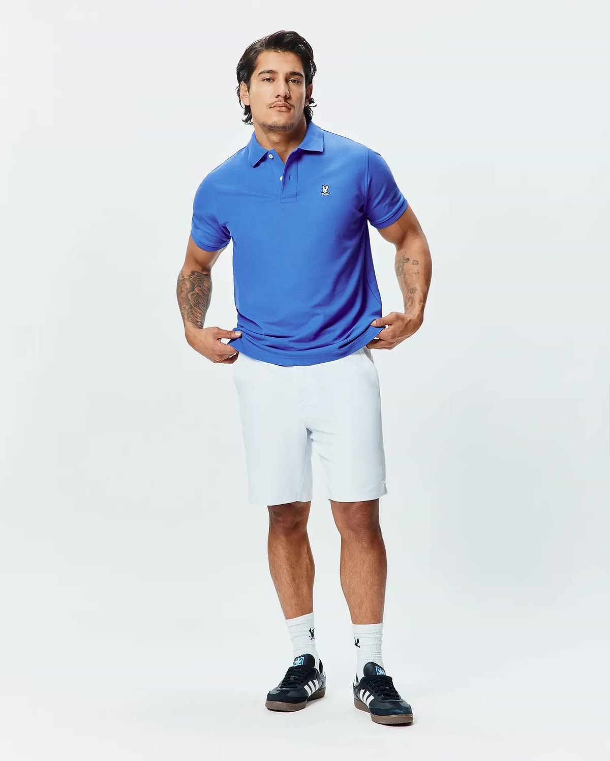 Royal blue pique polo shirt with a classic fit, red collar accent, and small white embroidered Psycho Bunny skull logo on the left chest, paired with white Mens Shiro Twill Short.