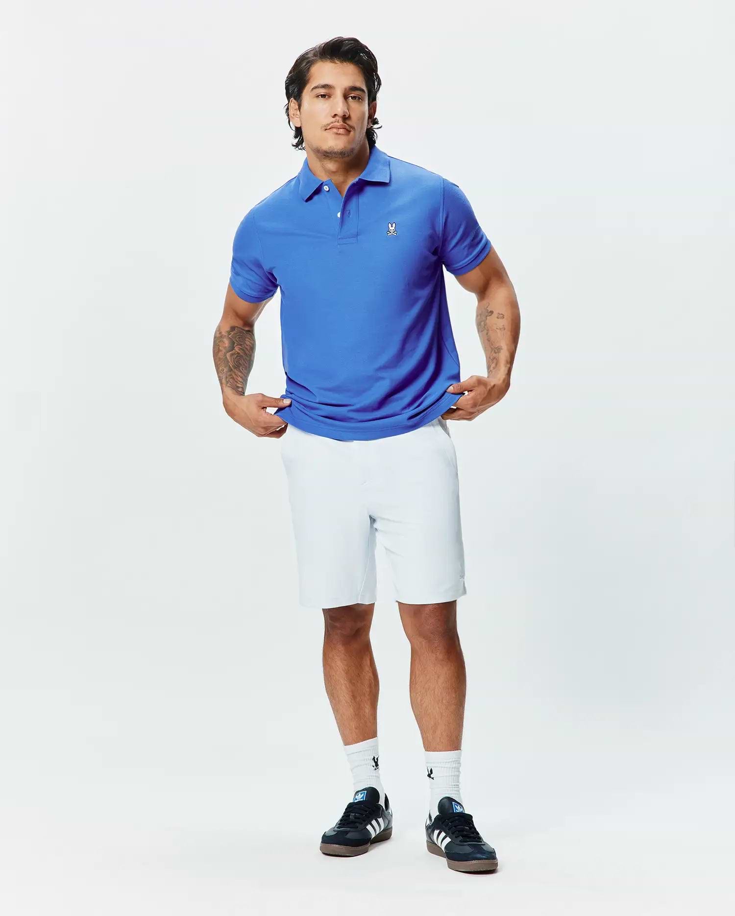 Royal blue pique polo shirt with a classic fit, red collar accent, and small white embroidered Psycho Bunny skull logo on the left chest, paired with white Mens Shiro Twill Short.