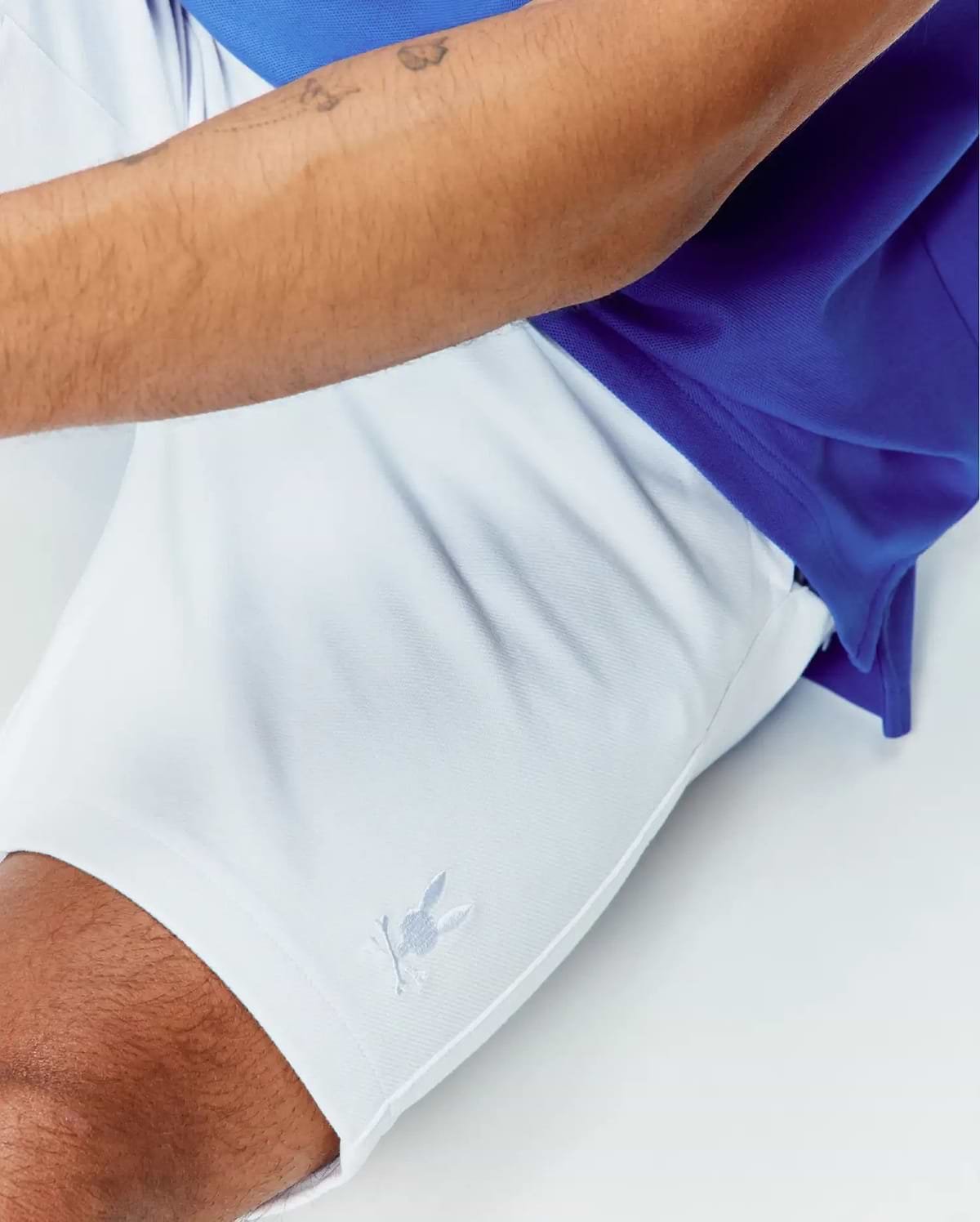 White Mens Shiro Twill Short featuring a small embroidered Psycho Bunny skull logo on the lower left leg, paired with a royal blue pique polo shirt, offering a classic fit.