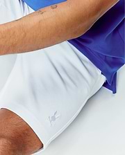White Mens Shiro Twill Short featuring a small embroidered Psycho Bunny skull logo on the lower left leg, paired with a royal blue pique polo shirt, offering a classic fit.
