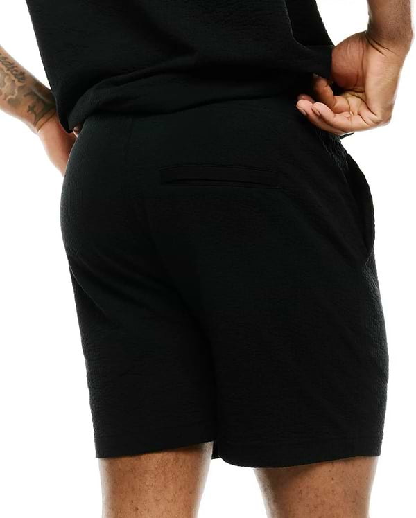Mens Arlen Seersucker Short, a premium black short with a distinctive puckered seersucker texture, offering a relaxed fit and featuring a discreet back welt pocket, embodying refined streetwear style.