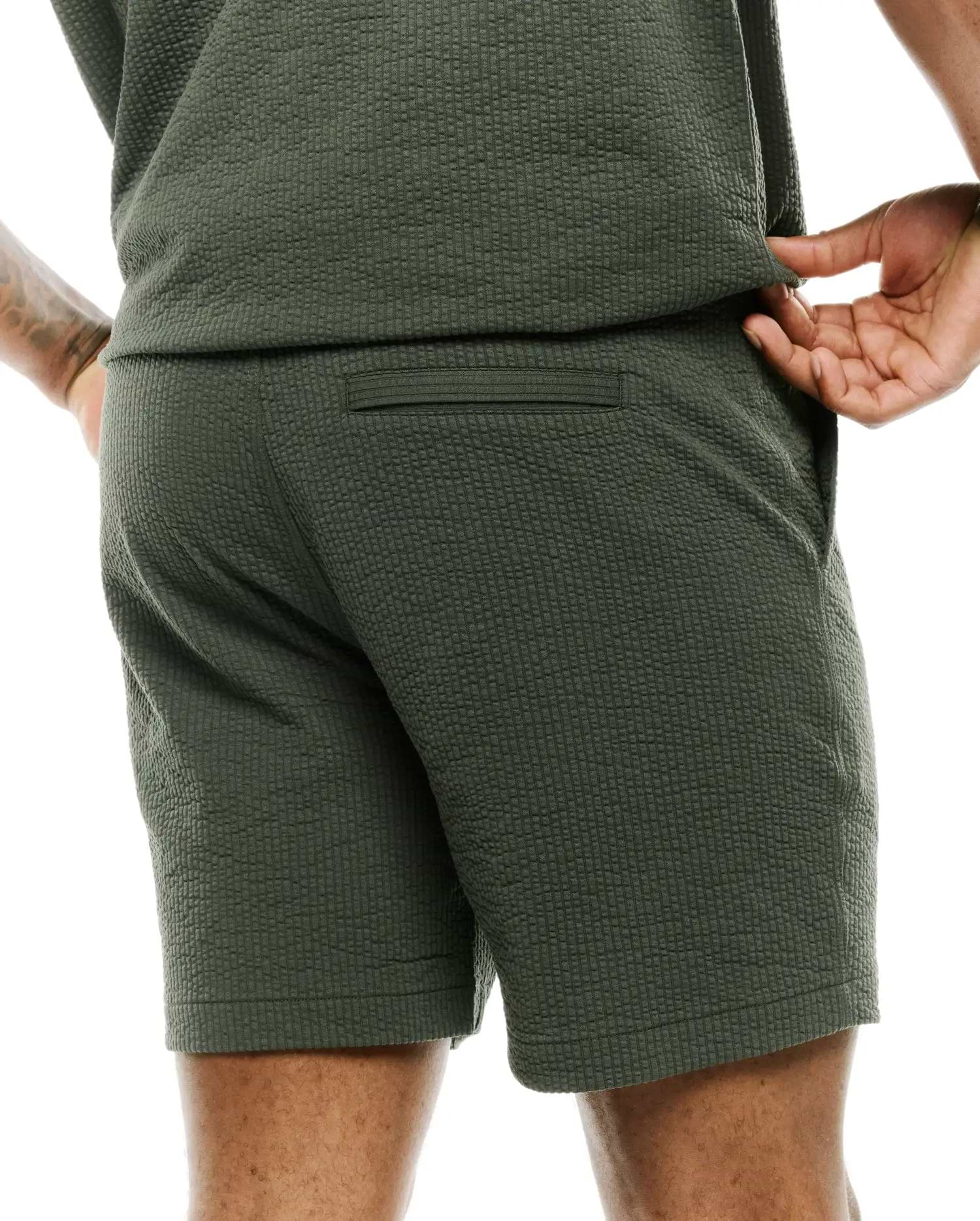 Mens Arlen Seersucker Short in dark olive green, featuring a classic fit, distinctive puckered seersucker texture, a subtle back welt pocket, and practical side pockets. (2)