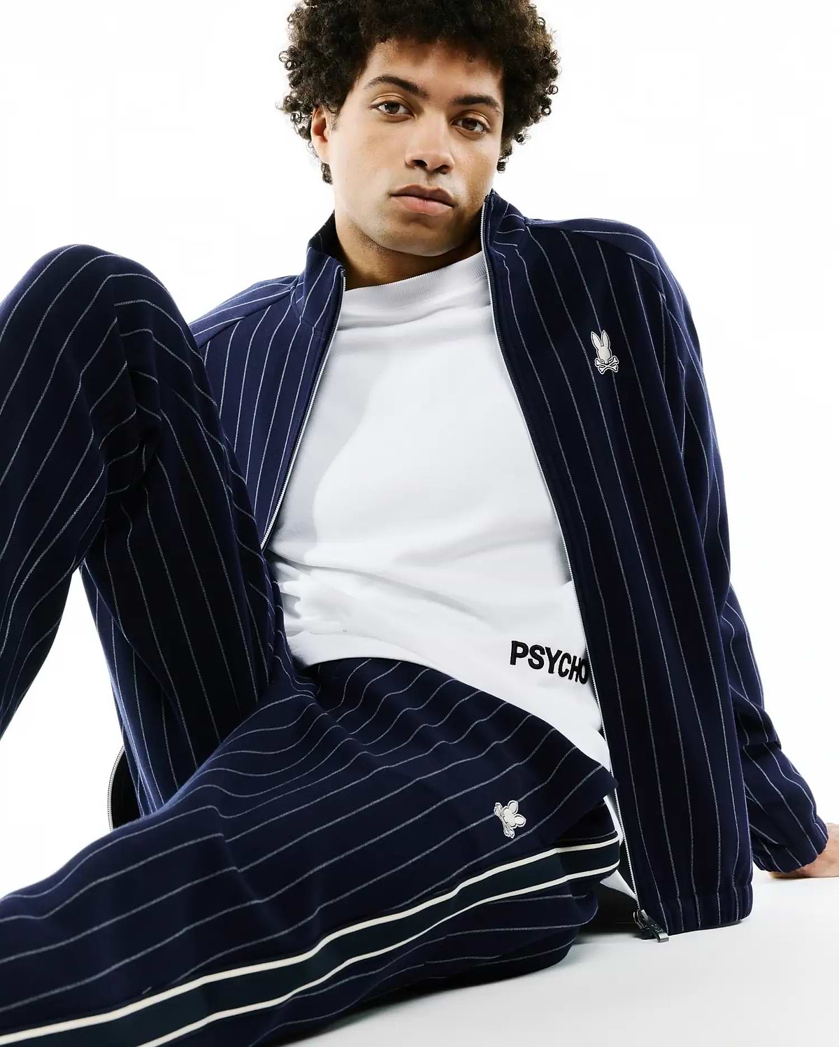 Navy blue chalk stripe track jacket with embroidered bunny skull logo on chest, matching Mens Harland Double Weave Chalk Stripe Track Pant with side stripes and logo, over a white PSYCHO t-shirt. (3)