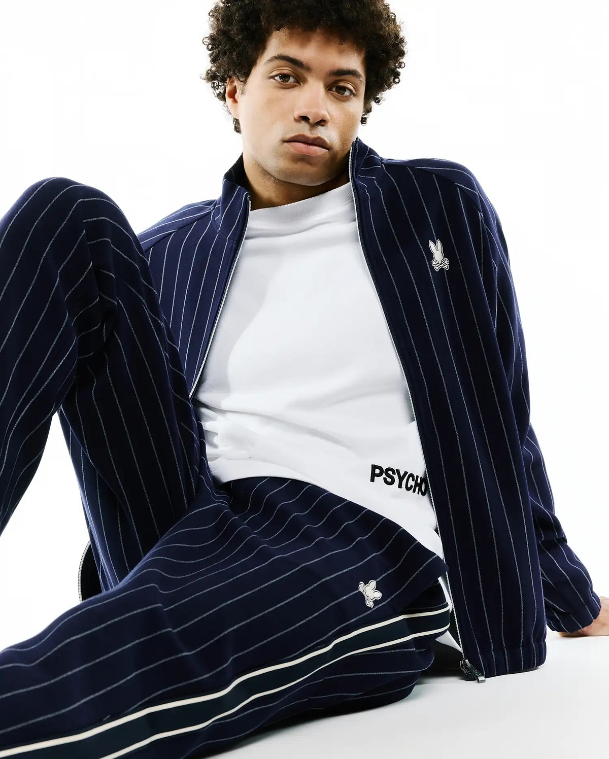 Navy blue chalk stripe track jacket with embroidered bunny skull logo on chest, matching Mens Harland Double Weave Chalk Stripe Track Pant with side stripes and logo, over a white PSYCHO t-shirt. (3)