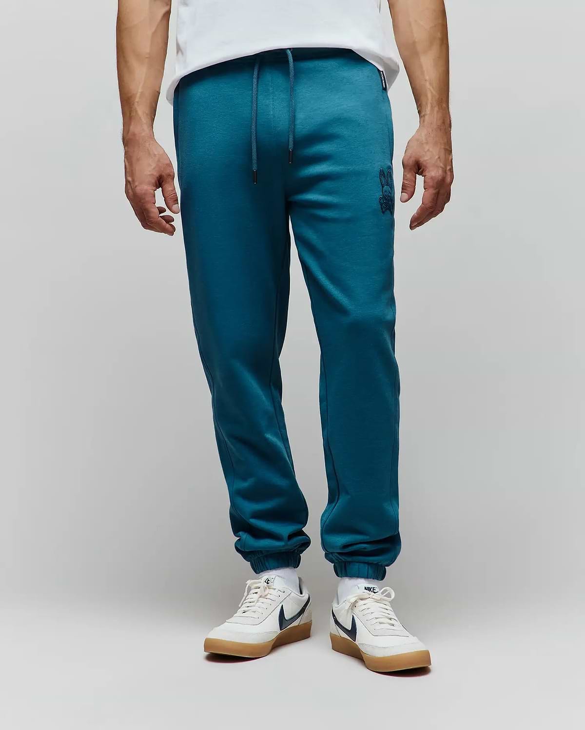 Mens Barry Joggers in deep teal, featuring a relaxed fit, soft jersey fabric, drawstring waist, ribbed cuffs, and a small tonal embroidered Psycho Bunny skull logo on the left thigh.